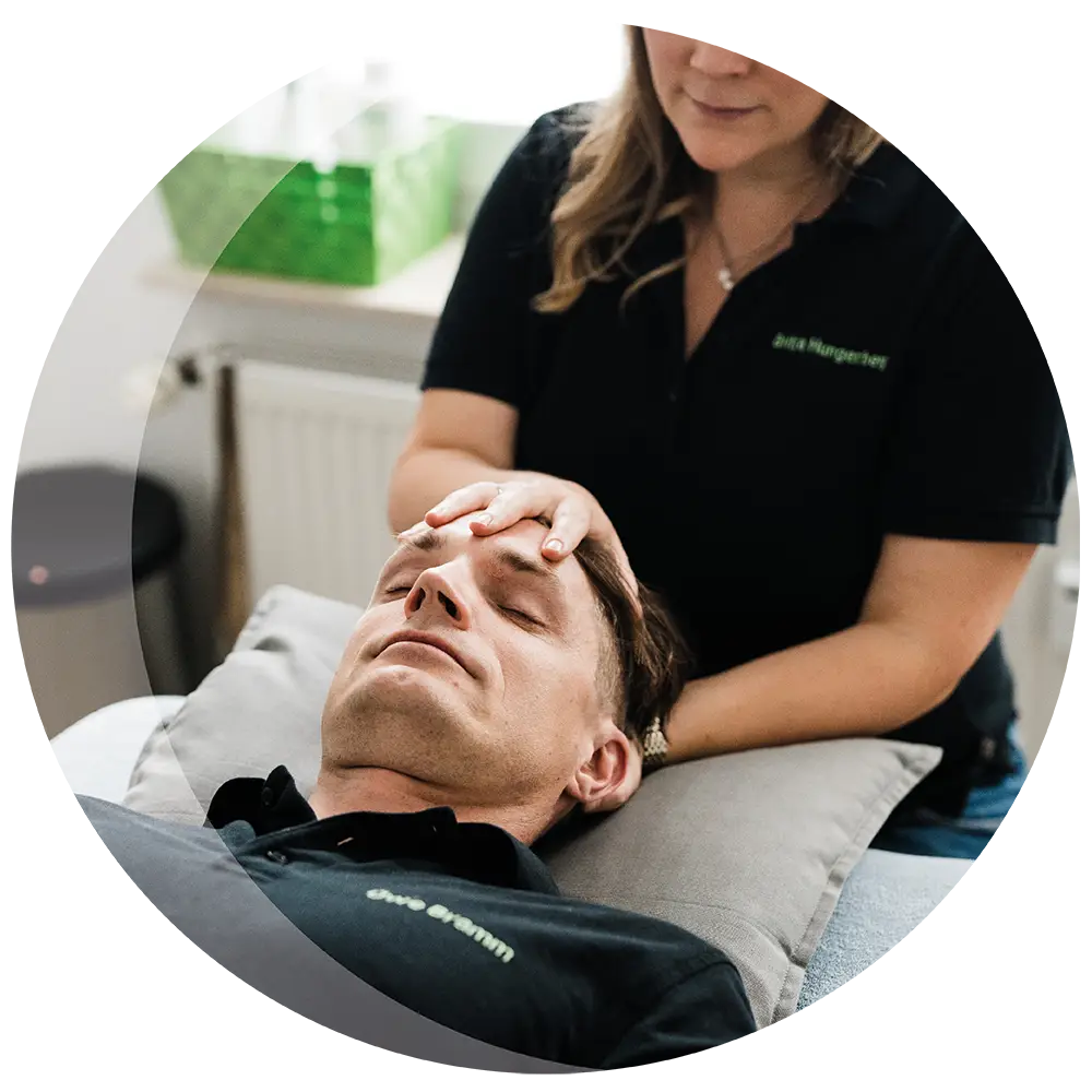 Detailfoto einer Behandlung, die Therapeutin hat die Hände auf der Stirn des Patienten