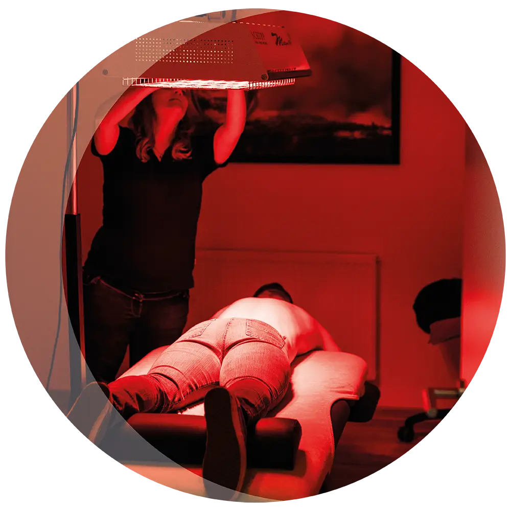 Wärmetherapie unter der Lampe: Ein Patient liegt auf der Liege unter dem roten Licht.