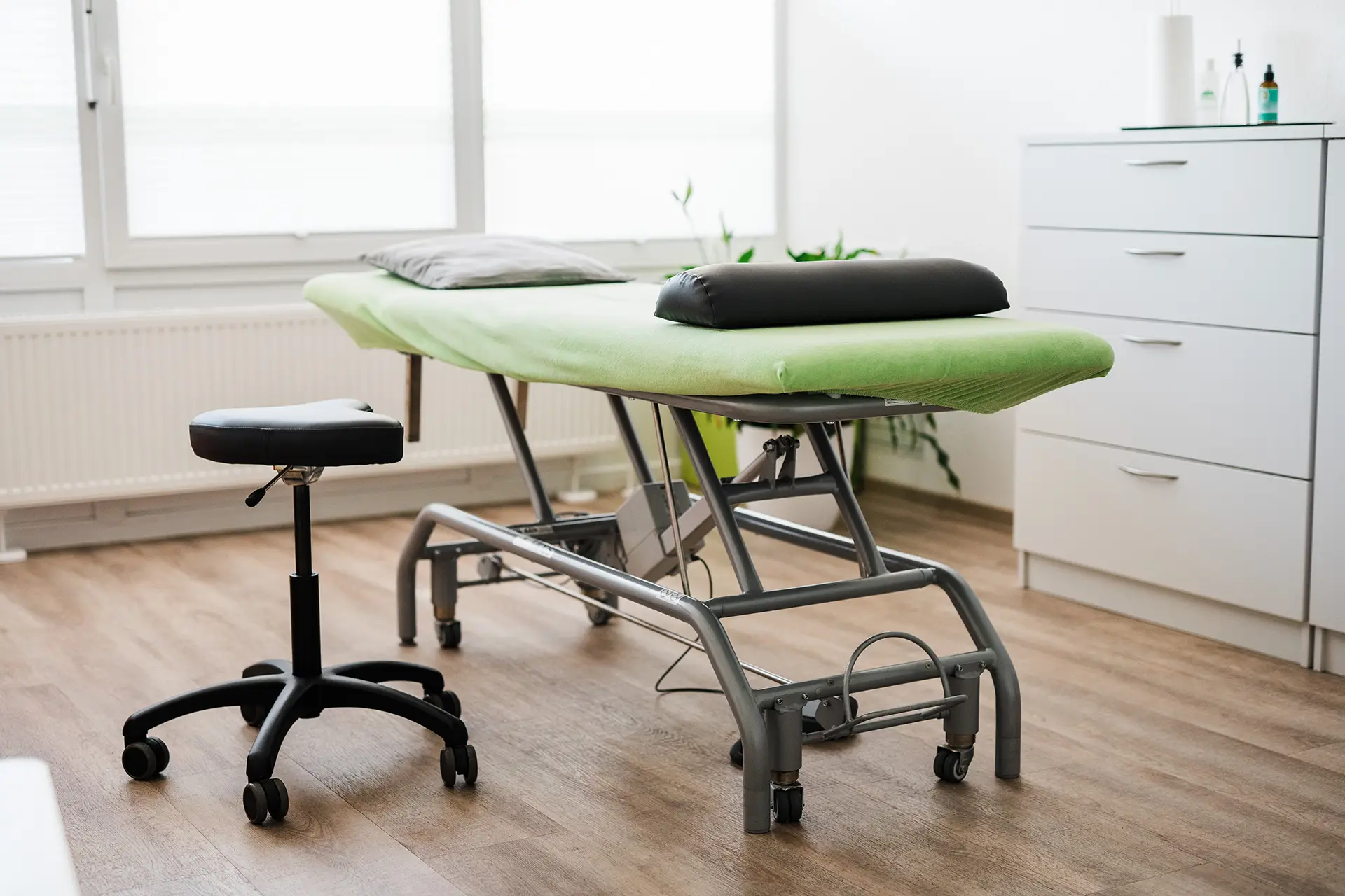 Praxisbild Physiotherapie heller modernen Praxisraum mit einer grünen Liege in der Mitte